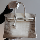 A staff member poses holding a rare Hermes handbag, the mat white Birkin Himalaya 35 during an auction preview at Christie's in Paris, France, March 4, 2016. REUTERS/Christian Hartmann - RTS9B2I